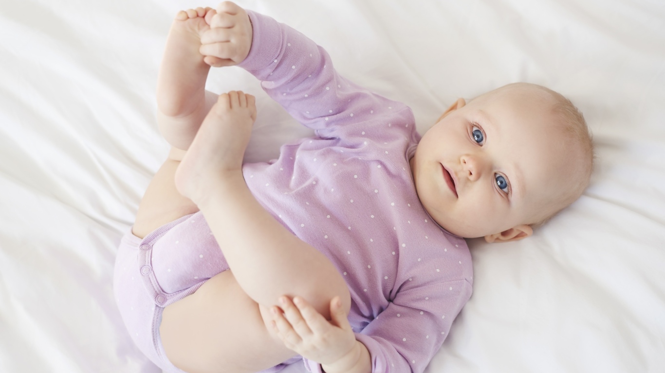 Милый голубоглазый малыш на белом покрывале