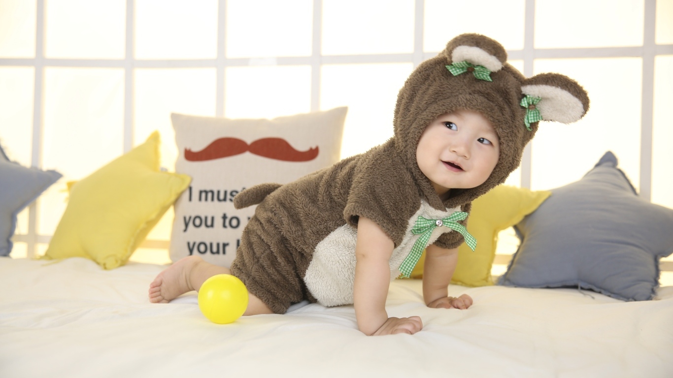 Смешной ребенок азиат в костюме на кровати