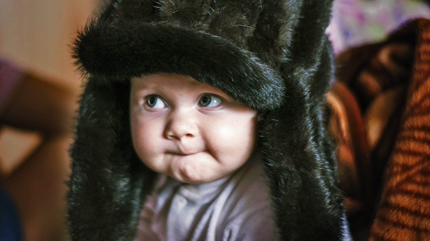 Смешной ребенок в черной меховой шапке