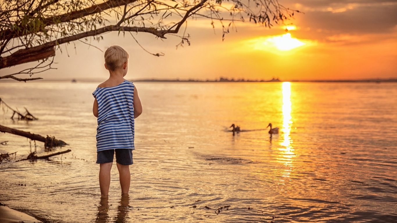 Маленький мальчик в тельняшке у озера на закате