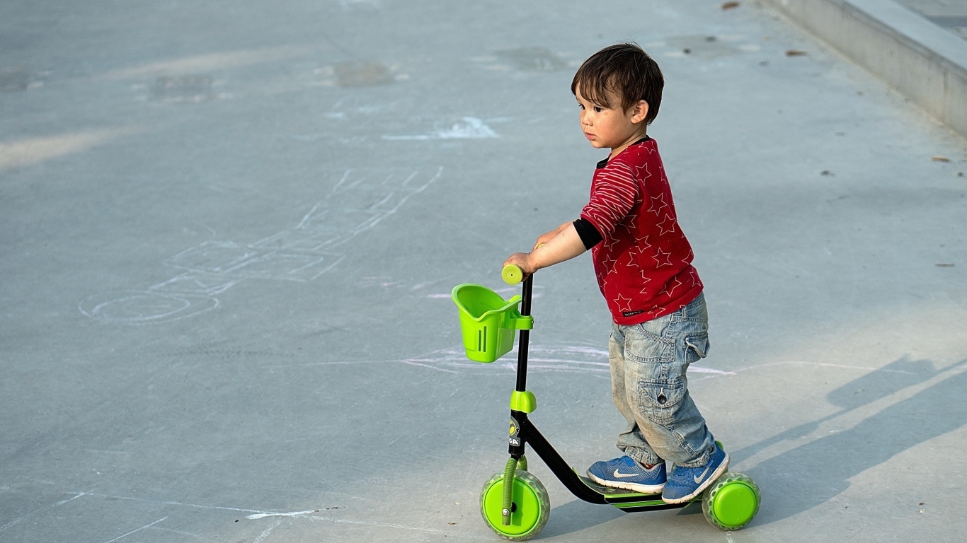 Маленький мальчик с зеленым самокатом