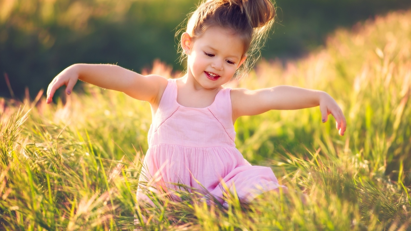 Маленькая девочка в розовом платье в зеленой траве
