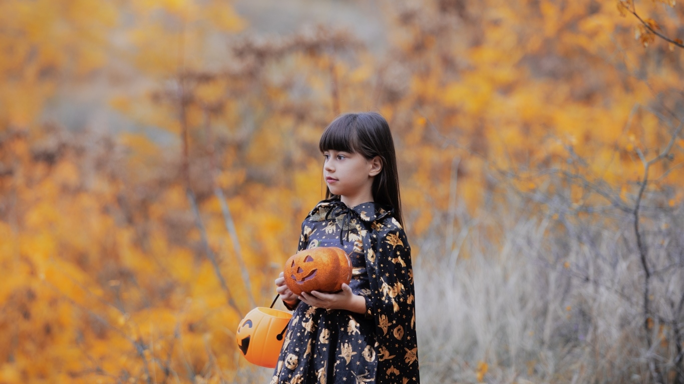 Маленькая девочка с тыквами в осеннем парке