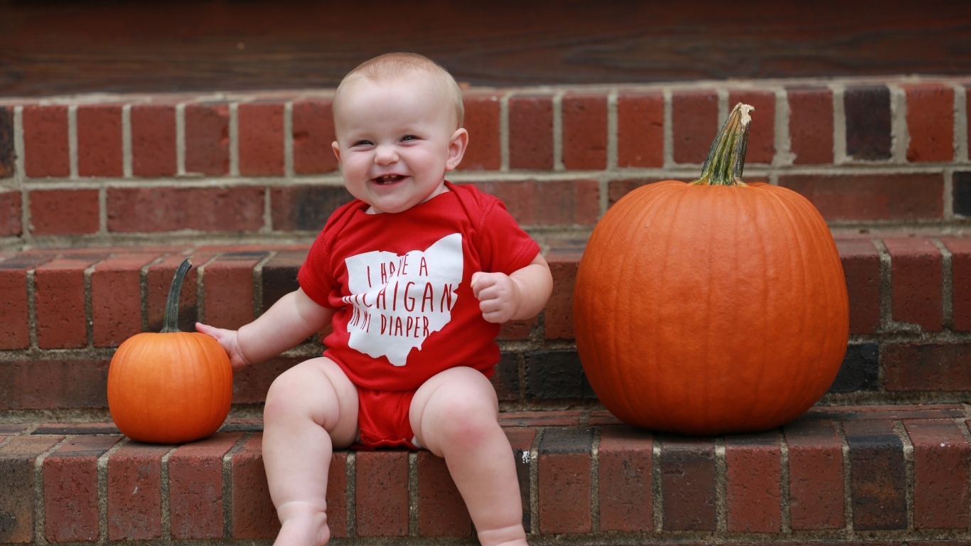 Маленький улыбающийся ребенок с тыквами на ступенях