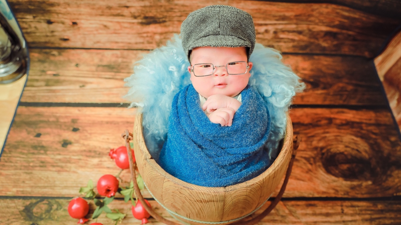 Новорожденный малыш в покрывале с кепкой на голове