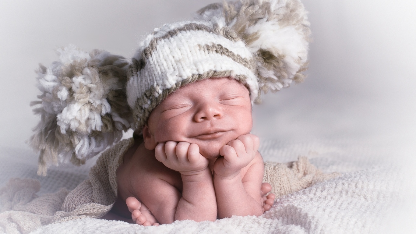 Новорожденный младенец в большой вязаной шапке