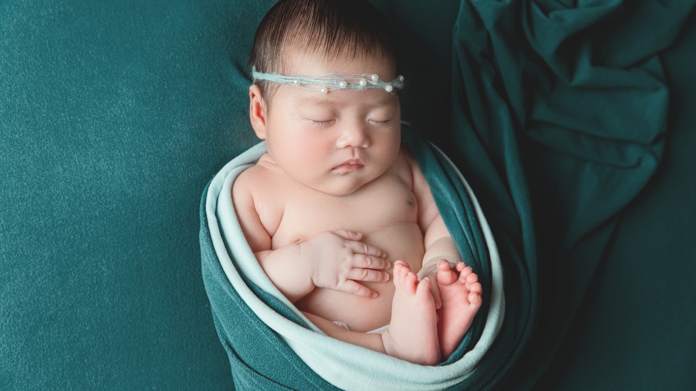 Фотография спящей новорожденной девочки на зеленом фоне