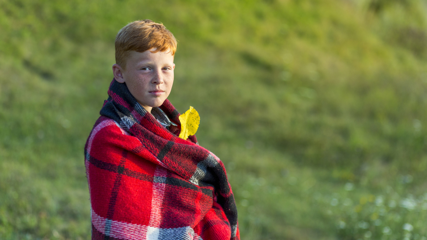 Рыжеволосый мальчик укутан пледом осенью 