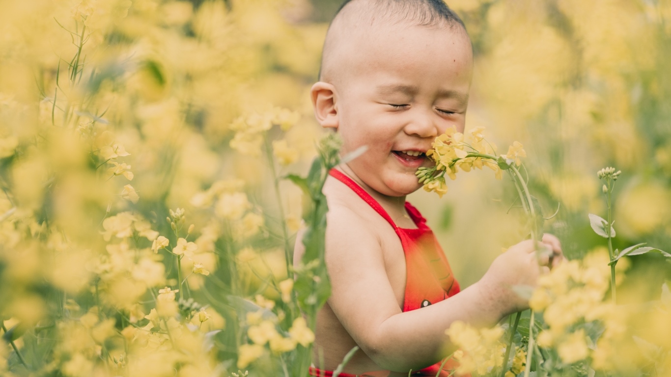 Улыбающийся ребенок на поле с желтыми цветами