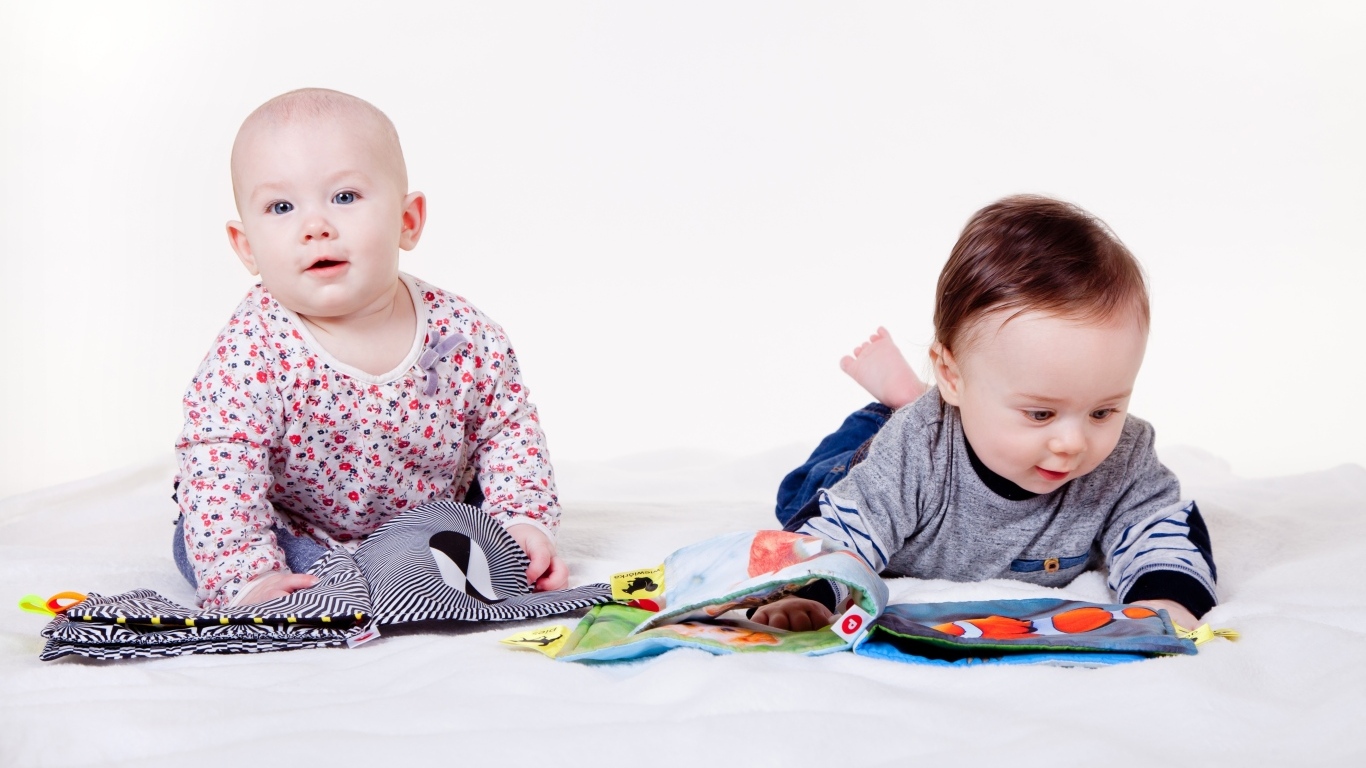 Два маленьких ребенка на кровати с мягкими книгами