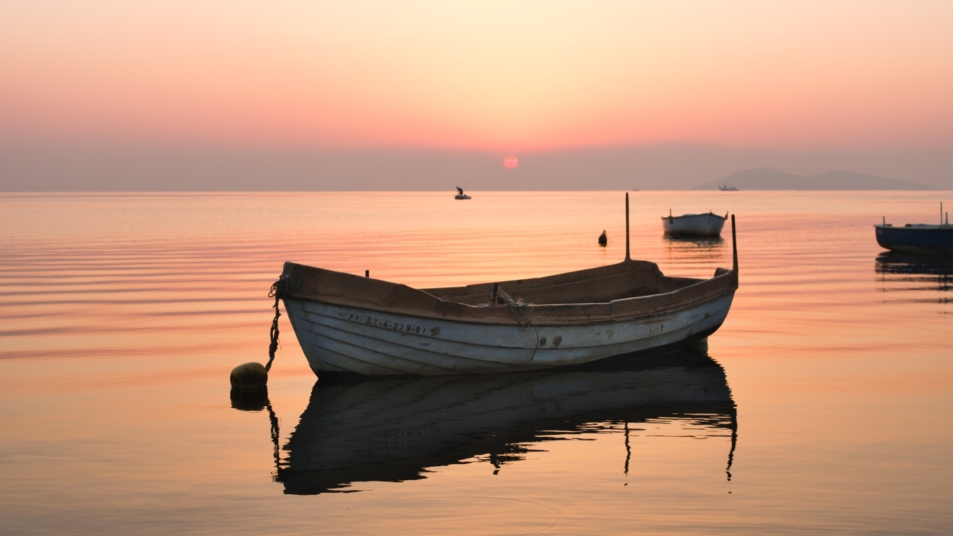 Старая лодка стоит на воде на закате солнца