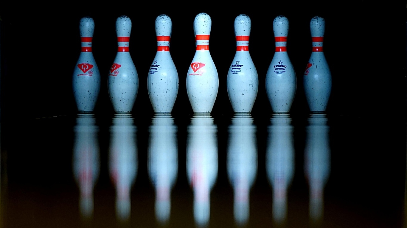 Кегли для боулинга отражаются в черной поверхности 