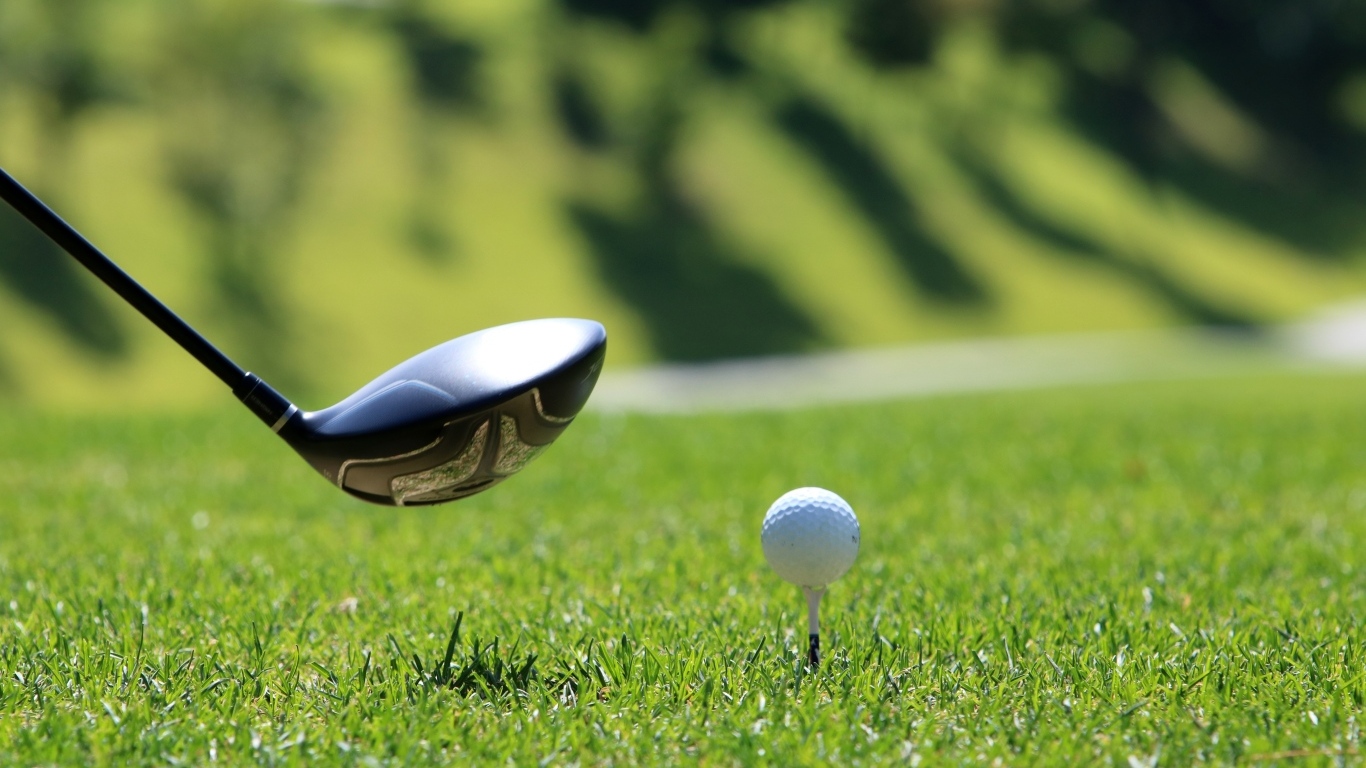 Golf ball and club on green grass