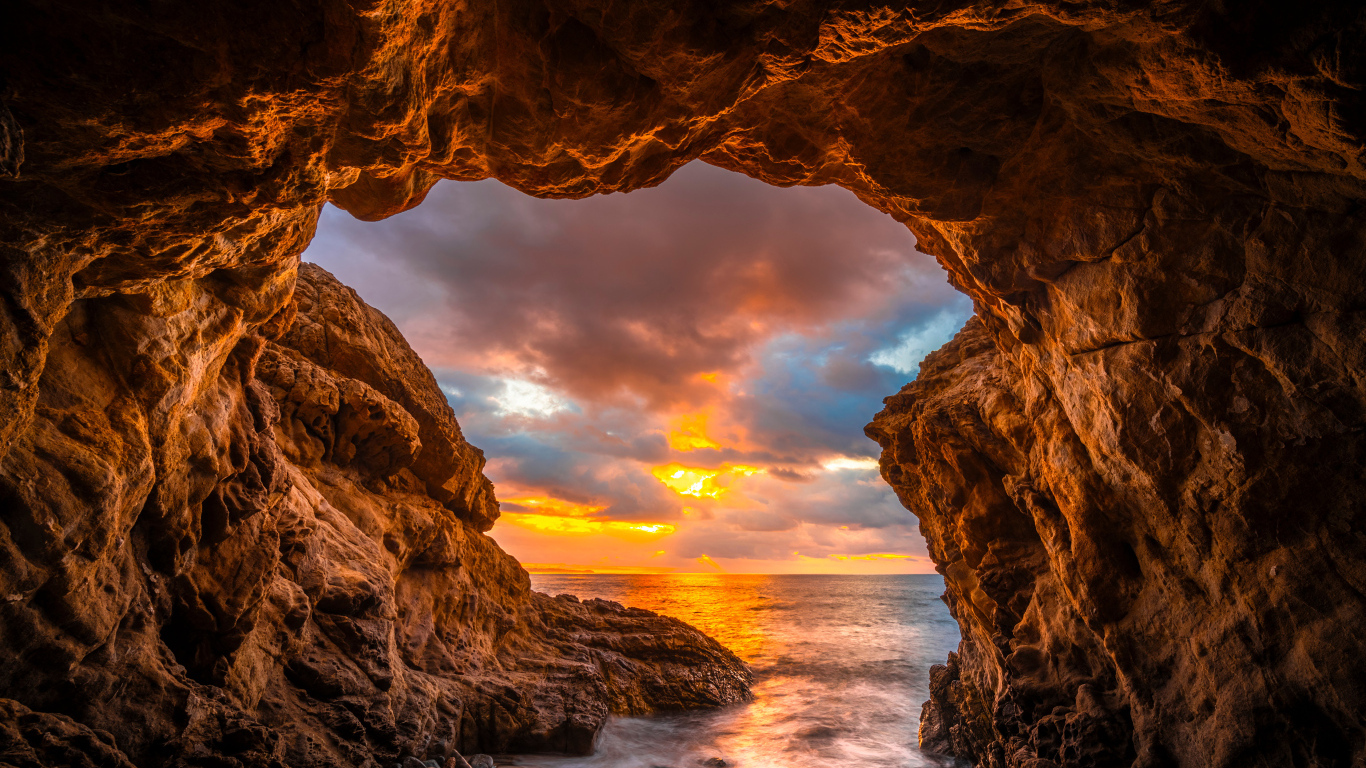 Арка в горе на закате солнца на пляже Малибу, США