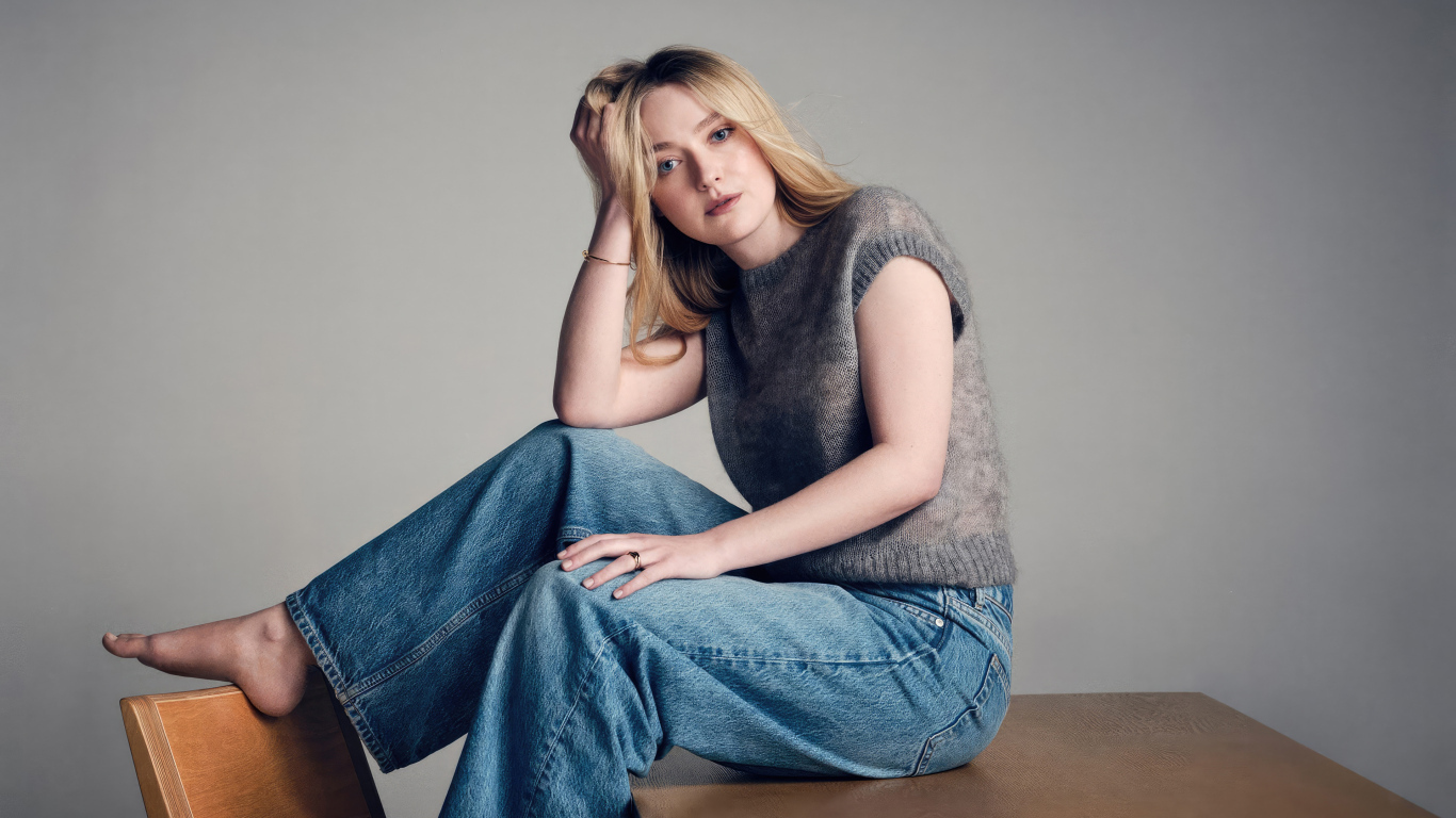 Актриса Дакота Фэннинг в джинсах сидит на столе