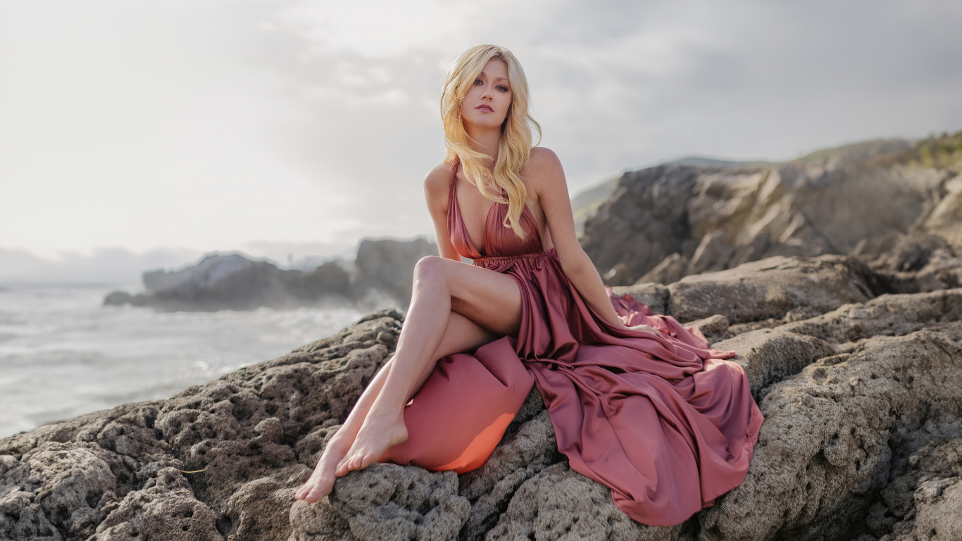 Актриса Кэтрин Макнамара сидит на камне у моря