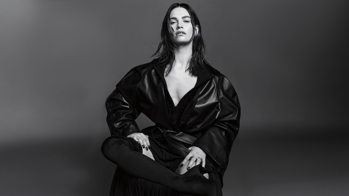 Актриса Лили Джеймс в черном наряде на сером фоне