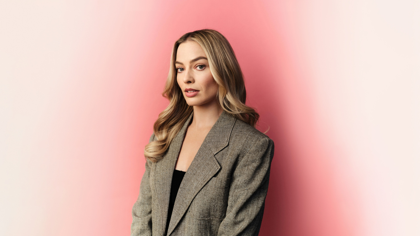 Актриса Марго Робби в сером пиджаке на розовом фоне