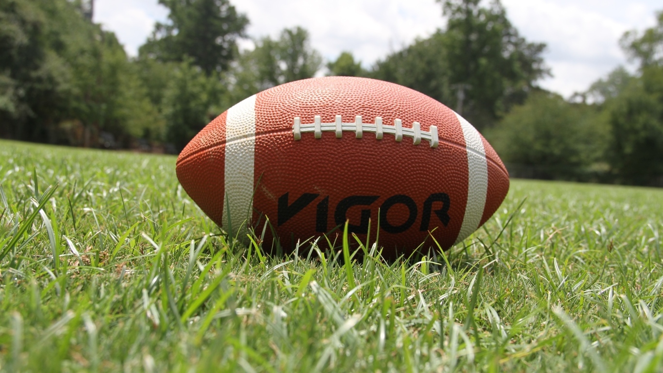 Мяч для американского футбола на зеленой траве 