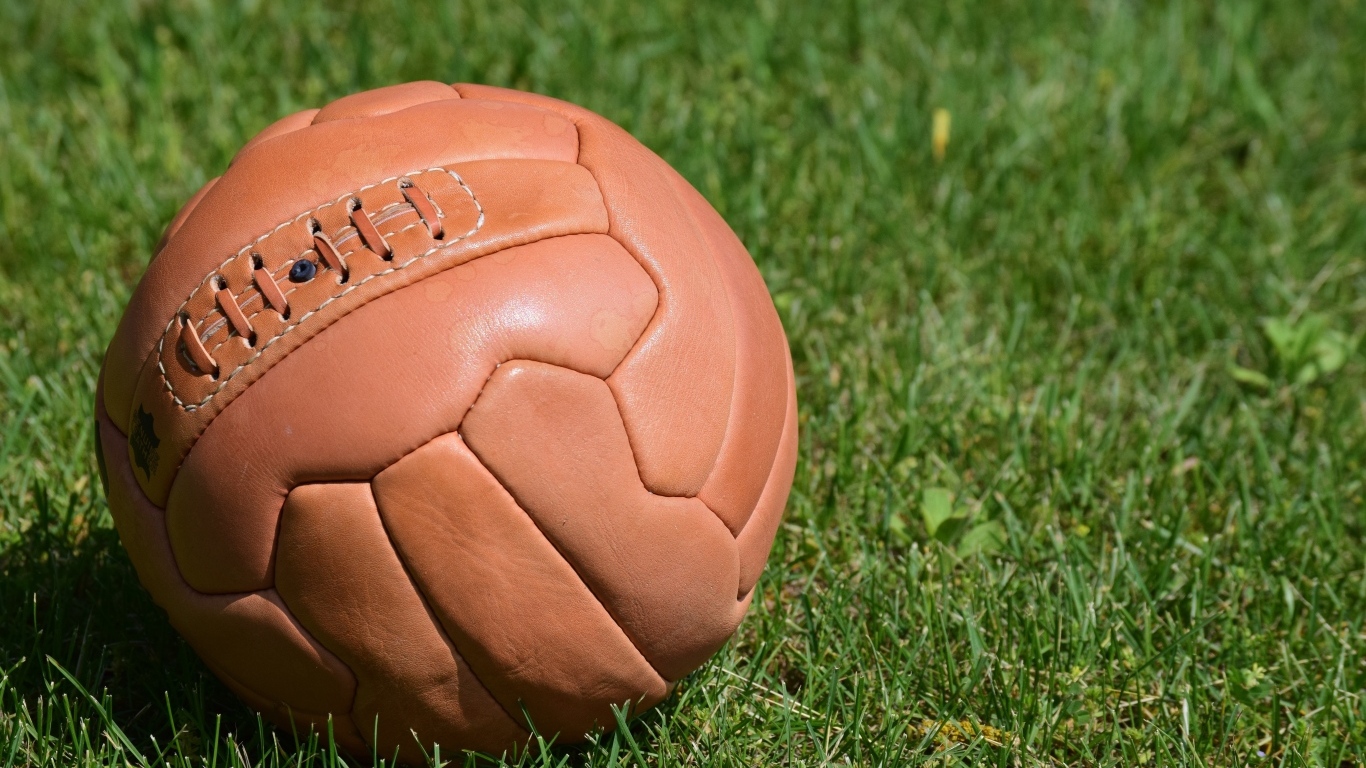 Коричневый кожаный мяч на зеленой траве 