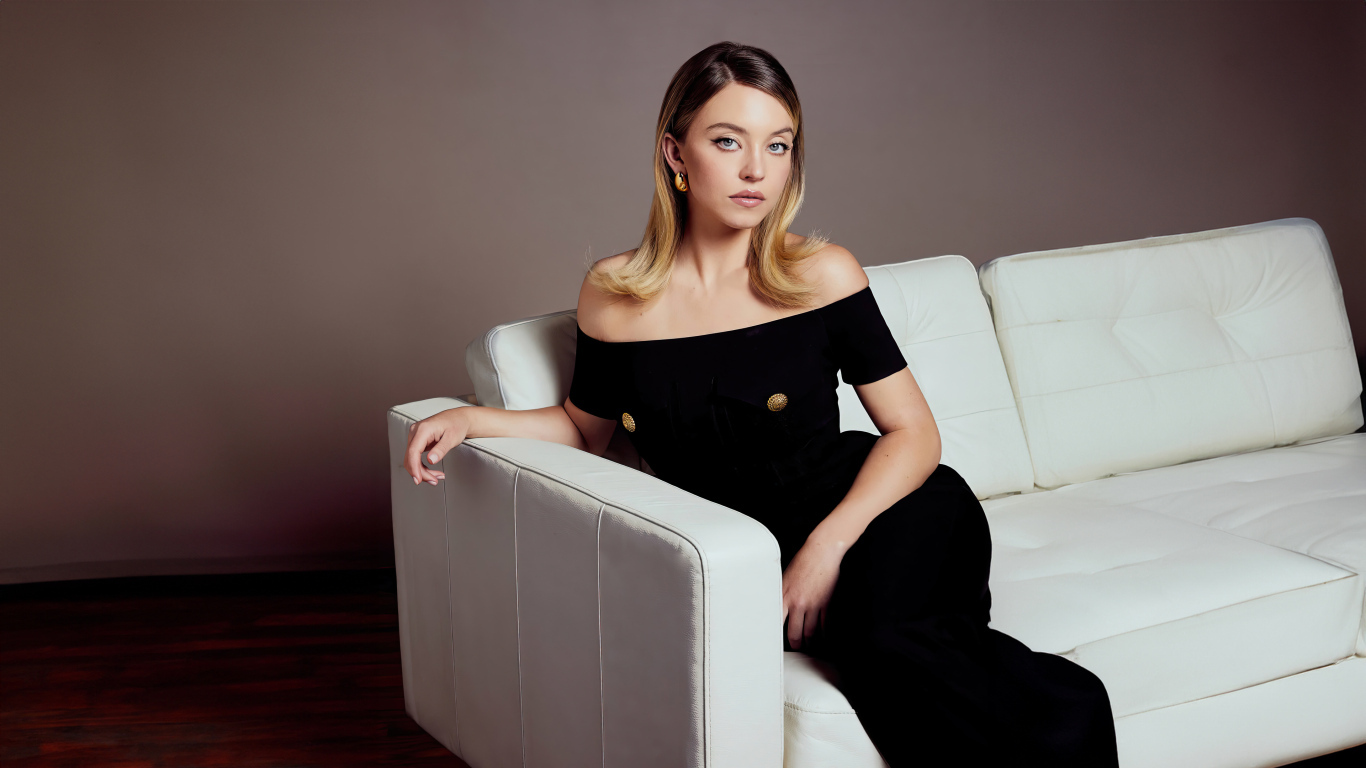 Милая девушка Сидни Суини в черном платье на диване