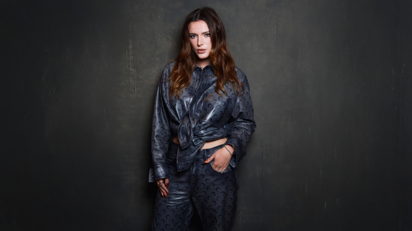 Рыжеволосая американская актриса Белла Торн в костюме на сером фоне