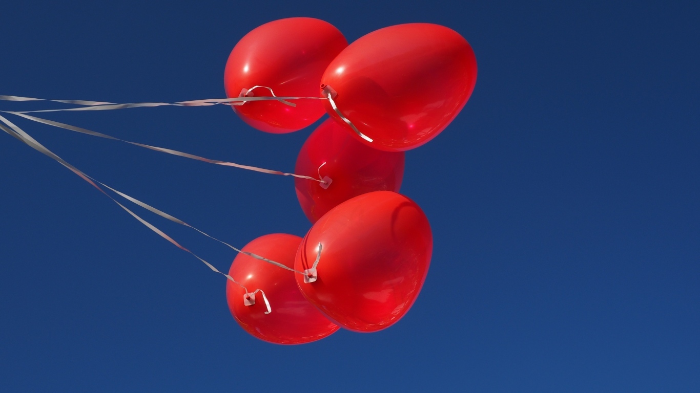 Красные воздушные шары на нитке на фоне голубого неба