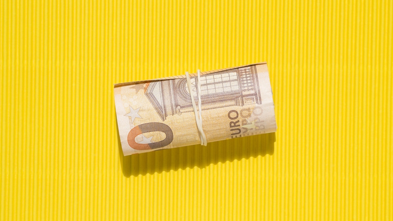 Сверток купюр евро на желтом фоне