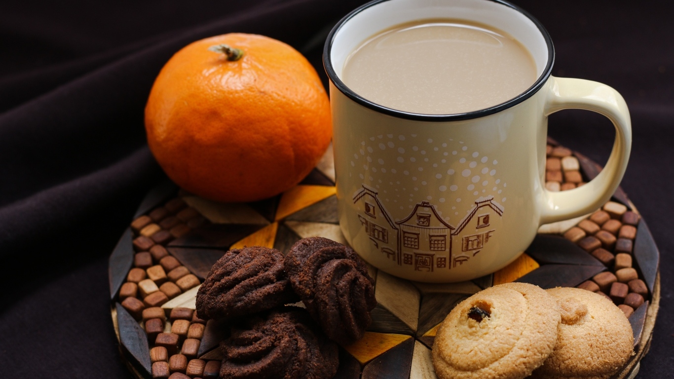 Чашка какао на тарелке с мандарином и печеньем