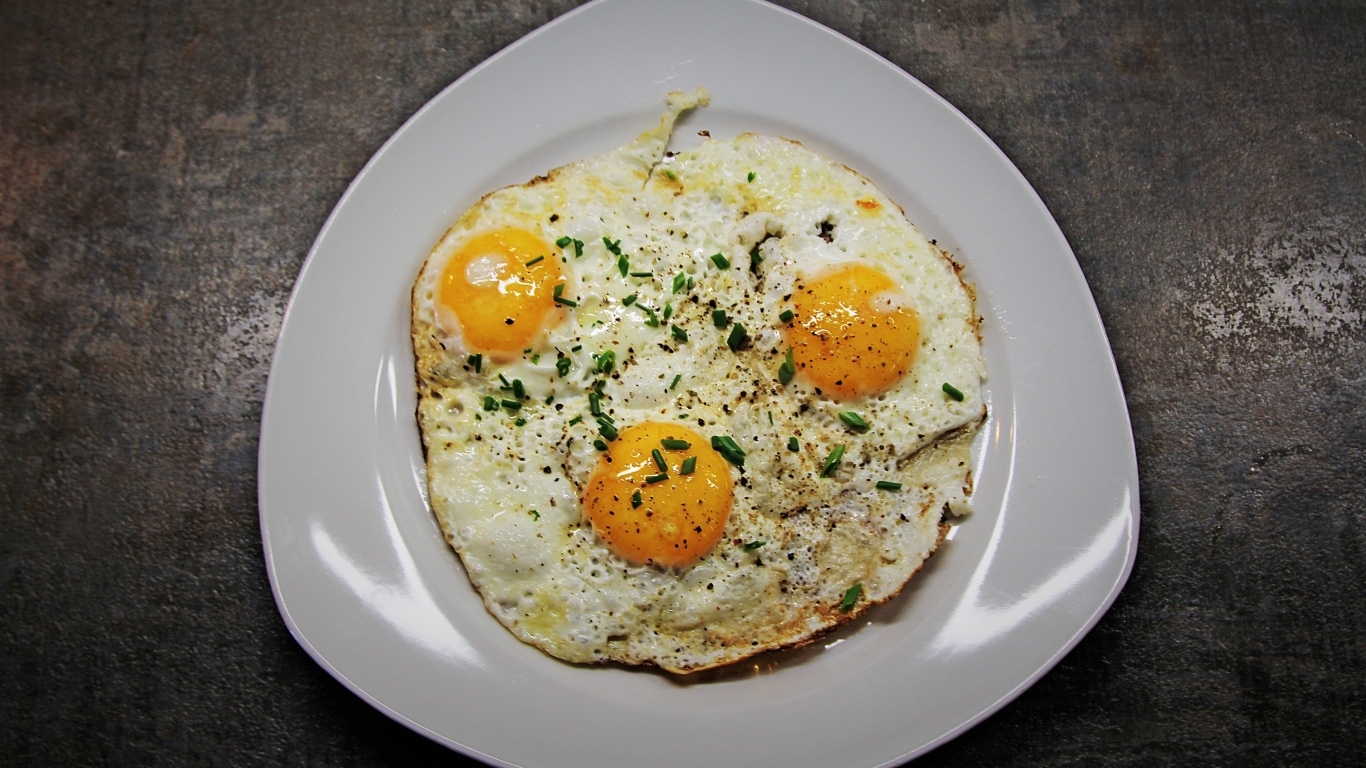 Яичница глазунья в тарелке на сером столе
