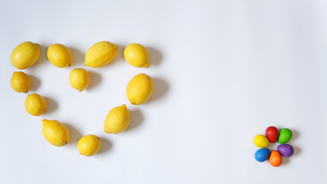 Сердце из желтых лимонов на сером фоне с конфетами