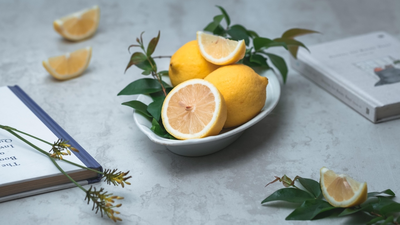 Лимон с зелеными листьями на столе с книгами