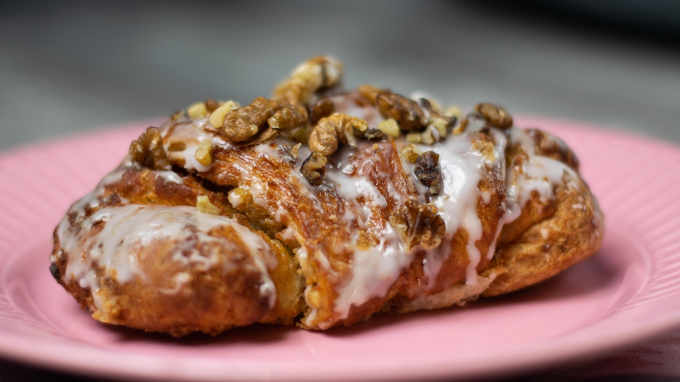Круассан с кремом и грецкими орехами на розовой тарелке