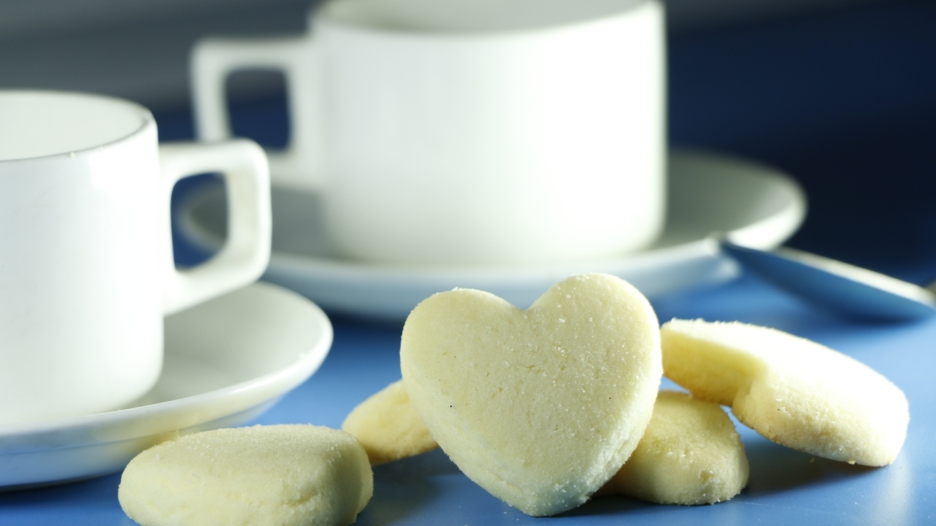 Сладкое печенье в форме сердца с кружками на столе