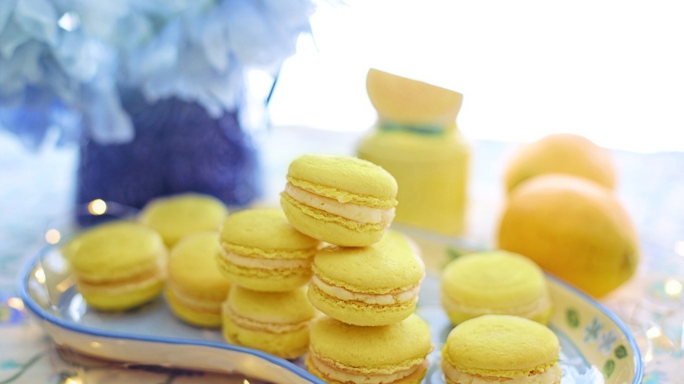 Десерт макарунс желтого цвета на тарелке на столе