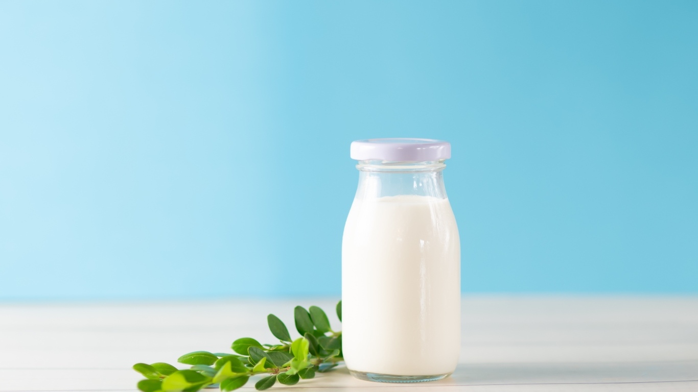 Бутылка молока с листьями на голубом фоне