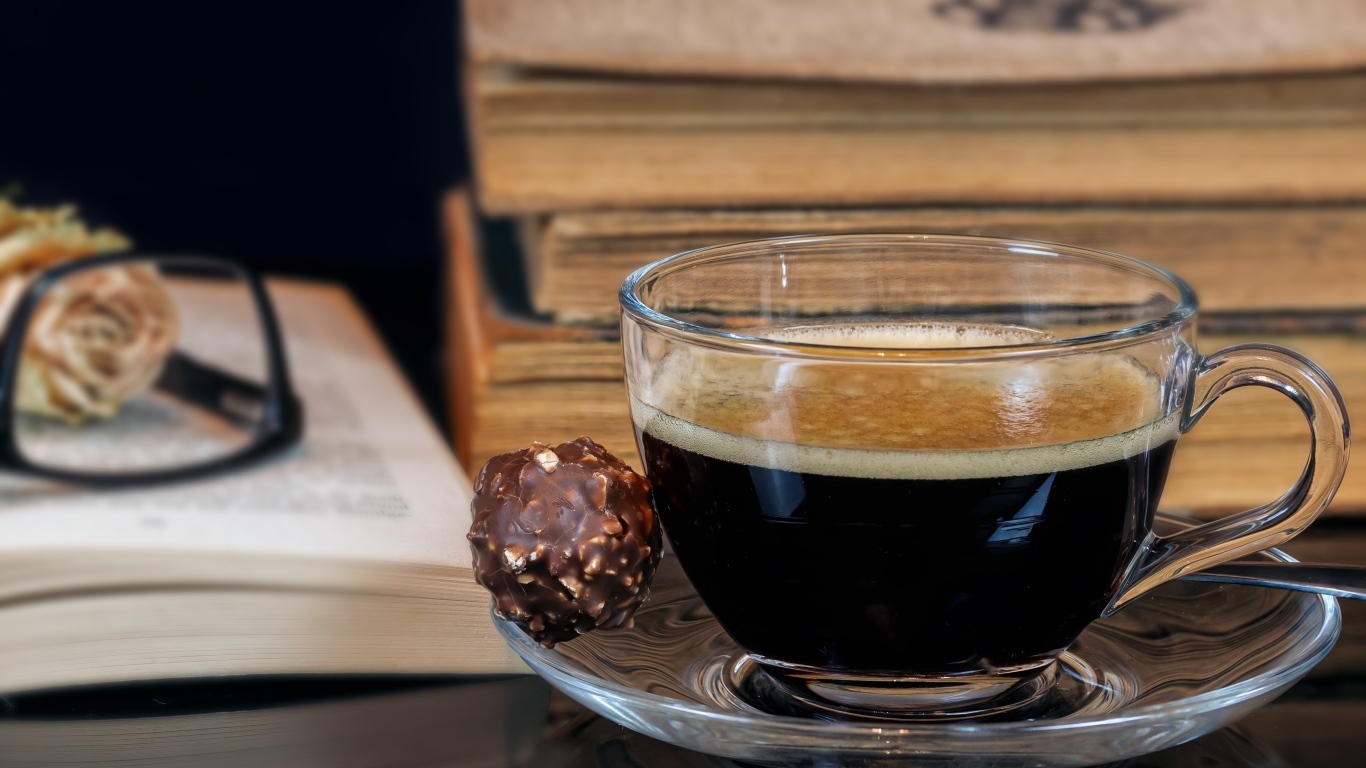 Чашка кофе на тарелке с шоколадной конфетой