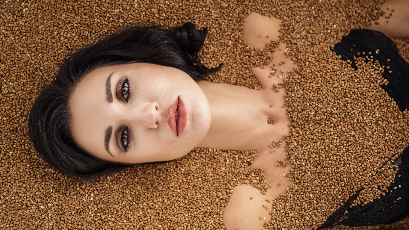 Красивая девушка лежит в зернах гречки