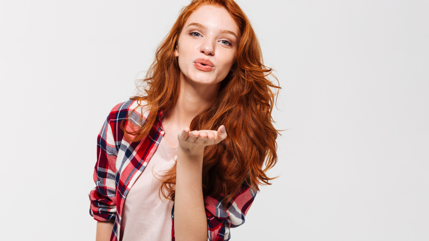 Красивая рыжеволосая девушка шлет воздушный поцелуй