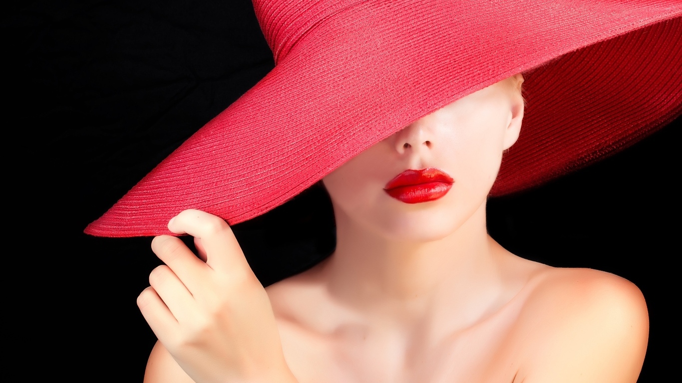 Девушка в большой красной шляпе на черном фоне