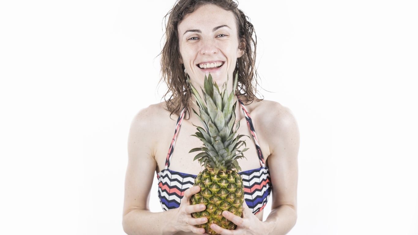 Улыбающаяся девушка с ананасом в руках
