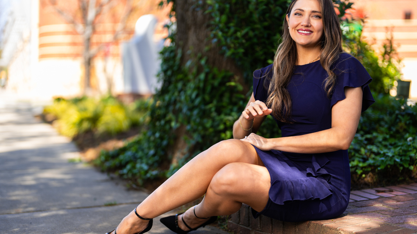 Улыбающаяся женщина в синем платье сидит на земле