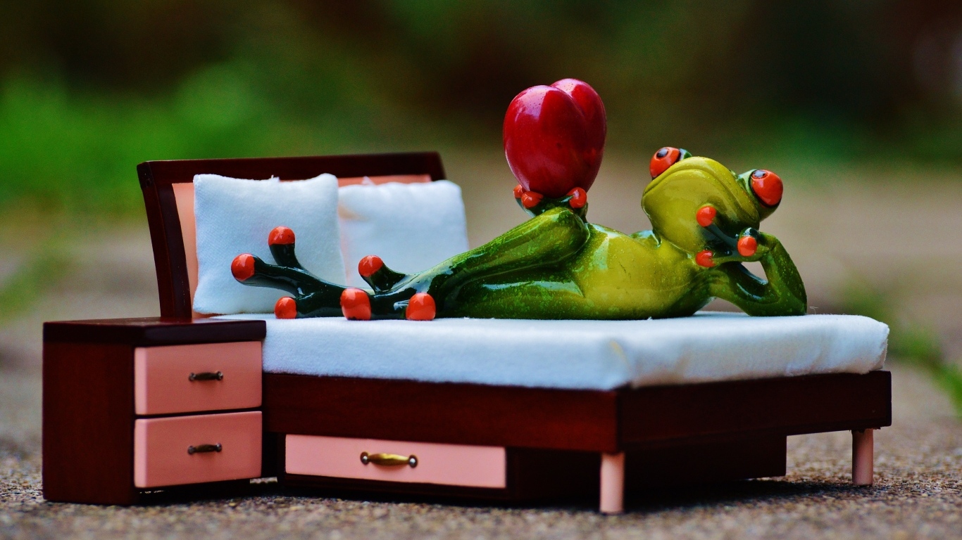 Фигурка зеленая лягушка с красным сердцем на кровати