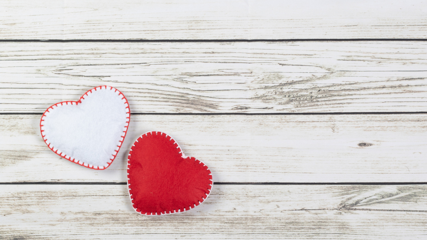 Белое и красное сшитое сердце на деревянном фоне