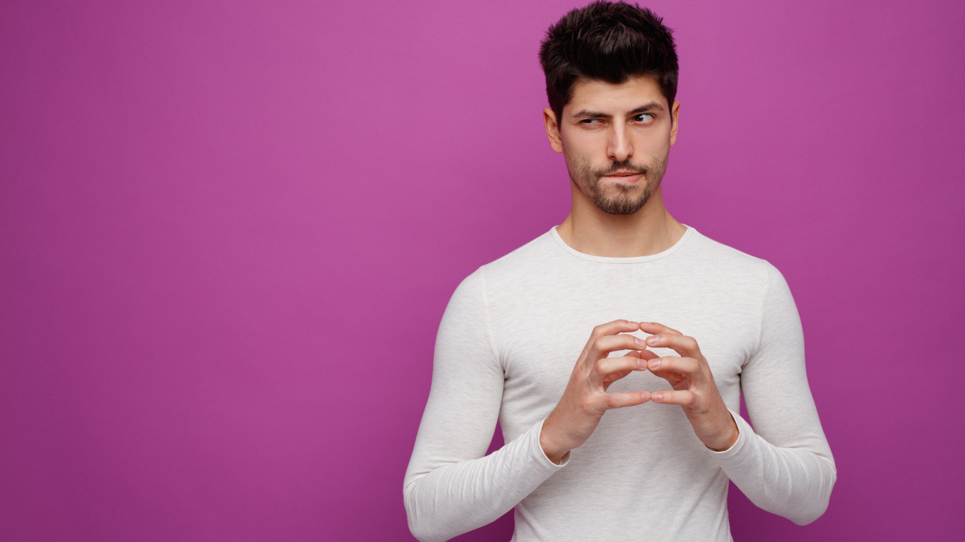 Хитрый мужчина в белом свитере на сиреневом фоне