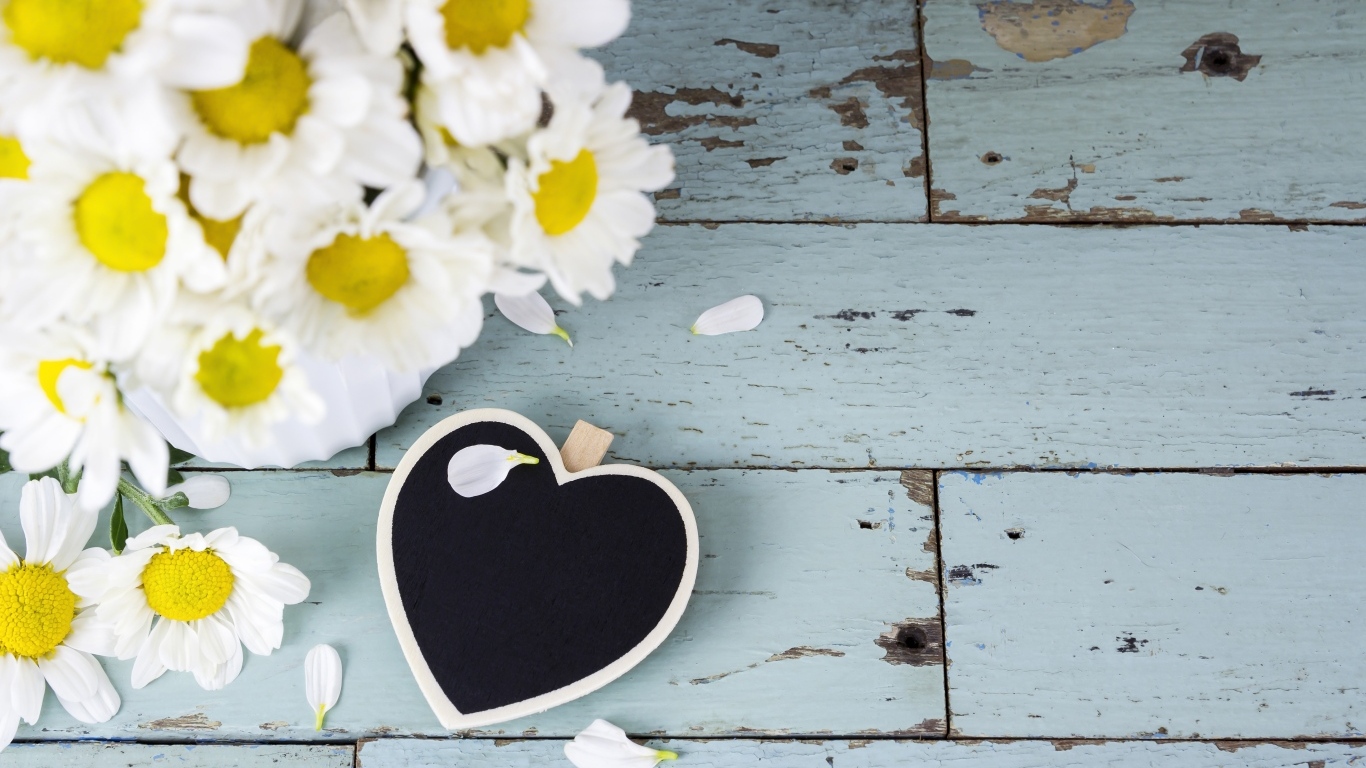 Черное сердце с букетом ромашек на сером столе