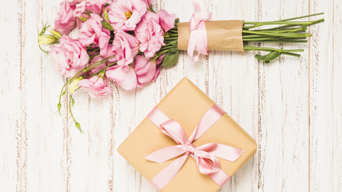 Букет розовых цветов эустомы с подарком на деревянном фоне