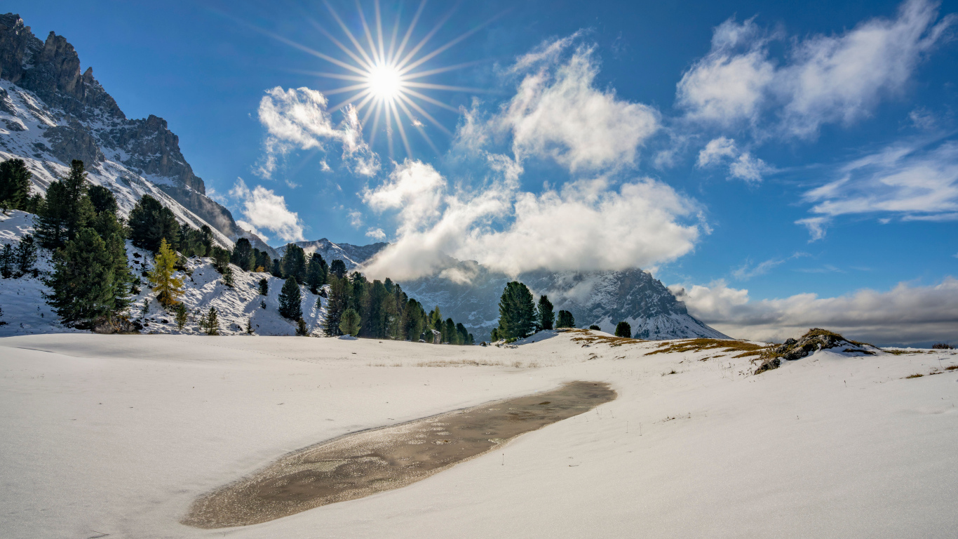 Яркое солнце над горами у заледеневшего озера
