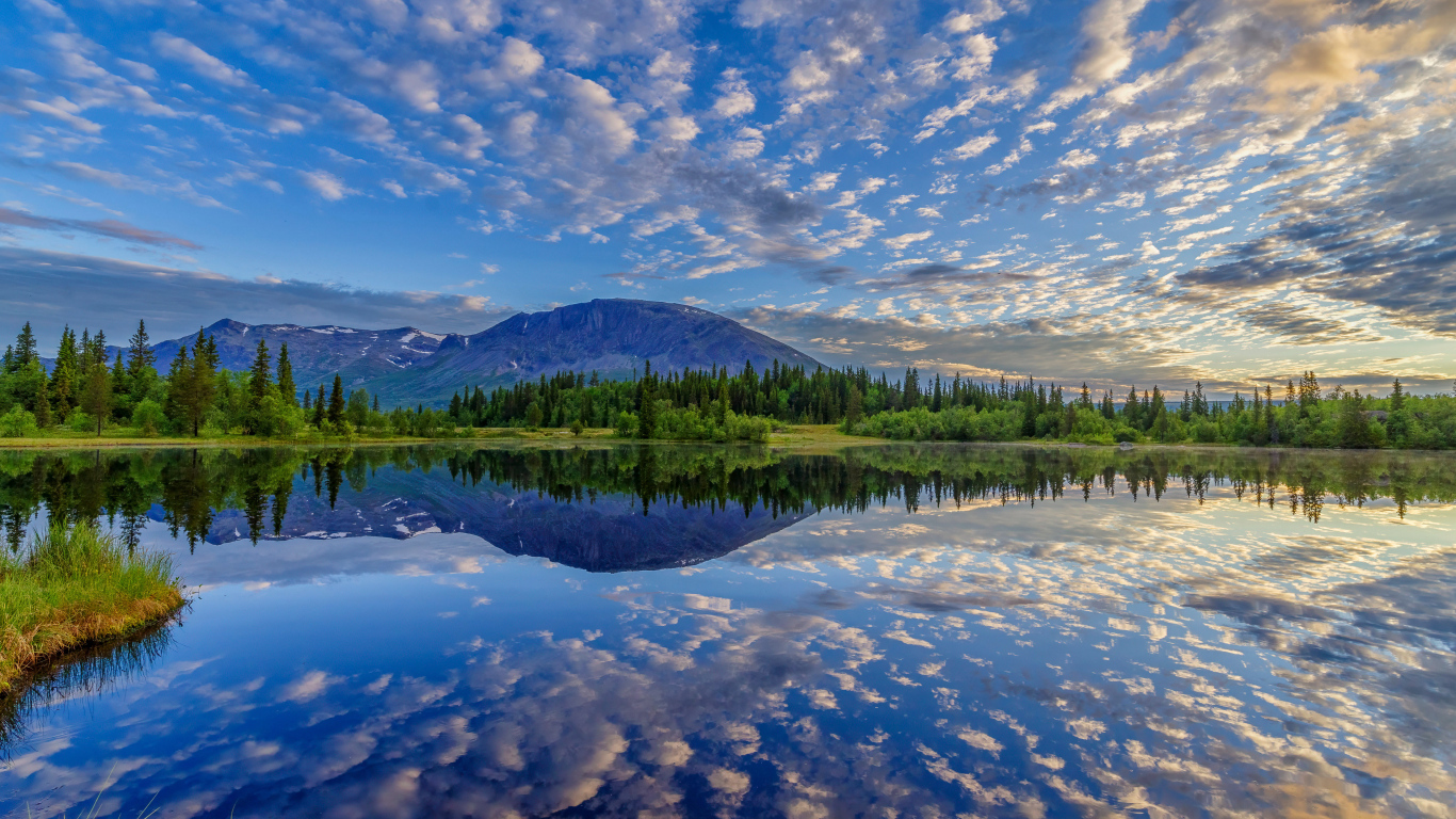 Красивое небо с облаками отражается в озере у гор