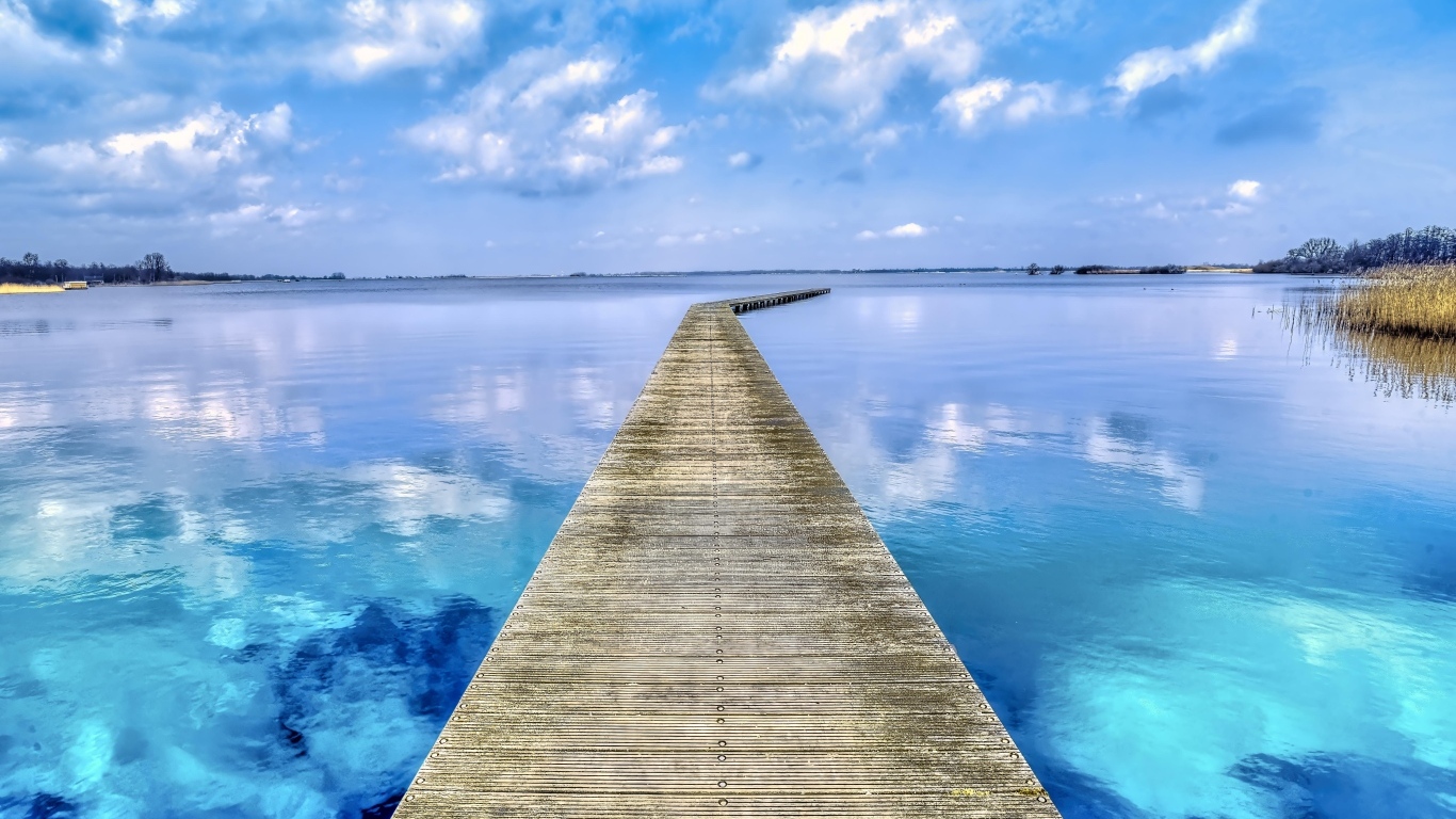 Деревянный мост у голубой воды озера летом